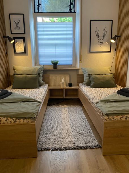 Schlafzimmer mit 3 Einzelbetten Zwei Einzelbetten mit grünen Kissen in einem hellen, gemütlichen Raum.