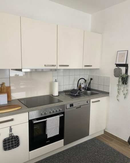 Voll ausgestattete Küche Moderne Küche mit Hellbeigen Schränken, Edelstahlgeräten und einer Arbeitsfläche.