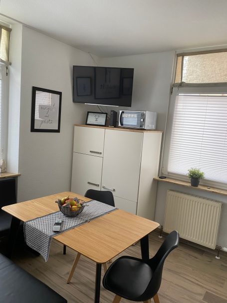 Sitzgruppe für bis zu 5 Personen Kleiner Essbereich mit Tisch, Stühlen, Mikrowelle und Pflanzen auf einem Fensterbrett.